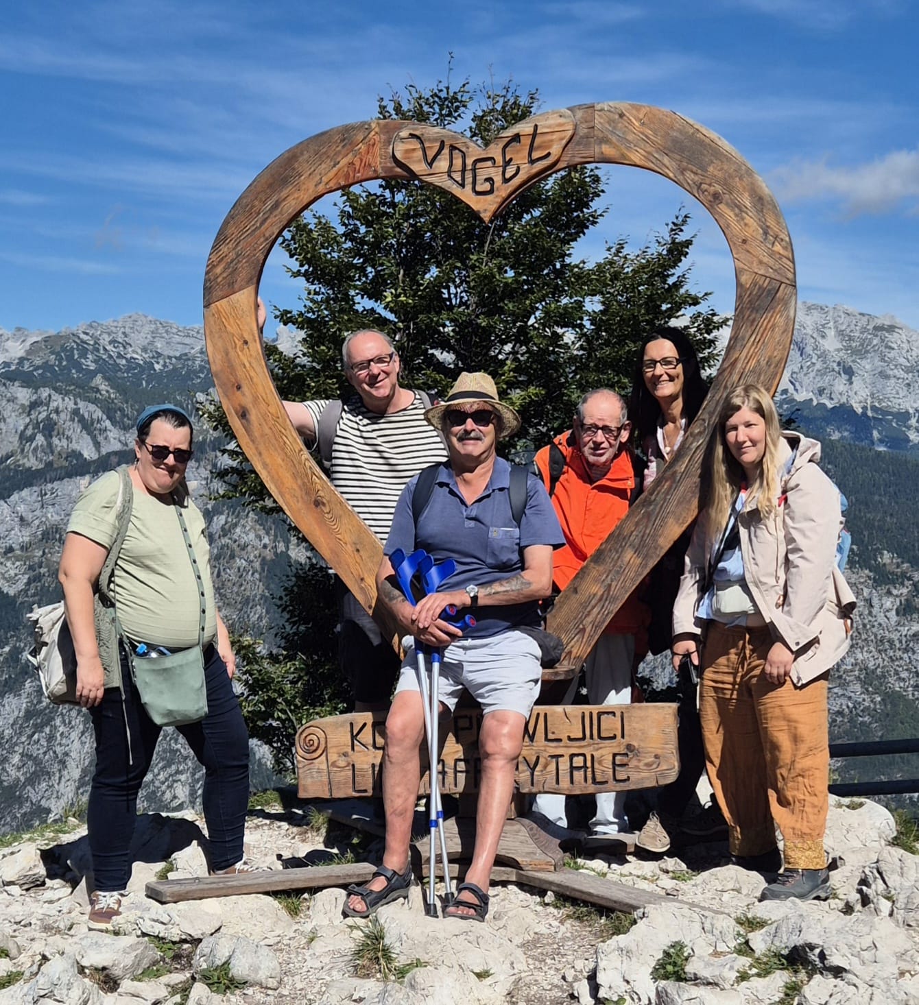 Reisegruppe mit Begleitpersonen auf einem Bergaussichtspunkt mit Panoramablick über die Berge
